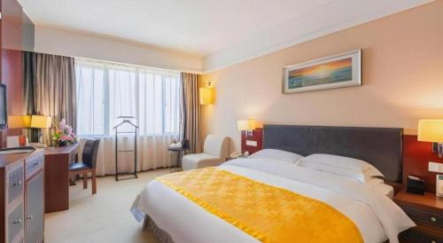 a hotel room with a large bed and a desk at Shantou Golden Gulf Hotel in Shantou