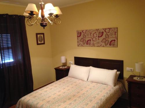 Un dormitorio con una cama con almohadas blancas y una lámpara de araña. en plaza artesania en La Barca de la Florida