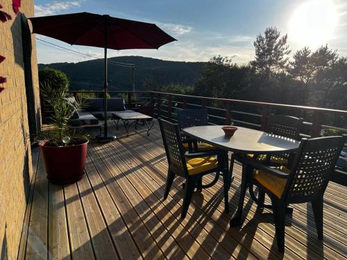 a wooden deck with a table and chairs and an umbrella at l'Ecrin des saisons in Manhay