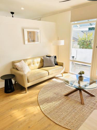 a living room with a couch and a glass table at Stunning Modern Self-contained Apartment in Burnside