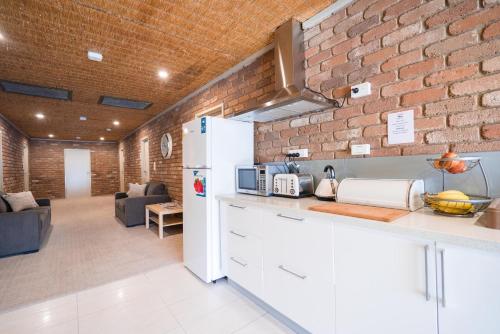 cocina con nevera blanca y pared de ladrillo en Farnham Court Motel and Restaurant, en Morwell