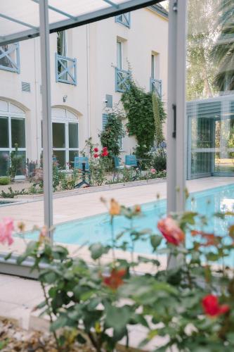 a house with a pool and flowers in the foreground at Hotel Aigue Marine in Tréguier