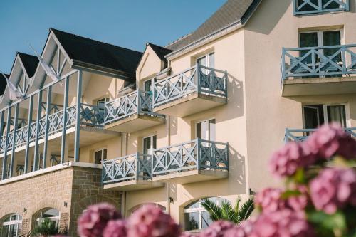 a building with blue balconies and pink flowers at Hotel Aigue Marine in Tréguier