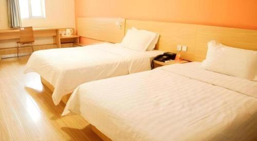 a hotel room with two beds and a telephone at 7 Days Inn West Gate of Taiyuan University of Technology in Taiyuan