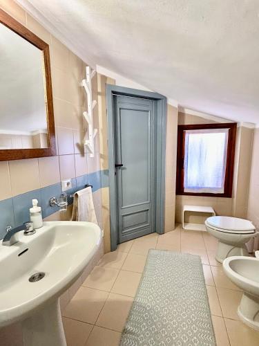 a bathroom with a sink and a toilet and a door at Nanni's House in Quartu SantʼElena