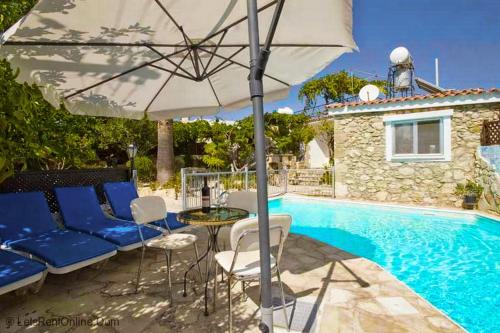 eine Terrasse mit einem Sonnenschirm und Stühlen sowie einem Pool in der Unterkunft Rose Garden Villa Peristerona in Peristerona