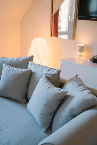 a couch with four pillows sitting in a room at Hotel Aigue Marine in Tréguier