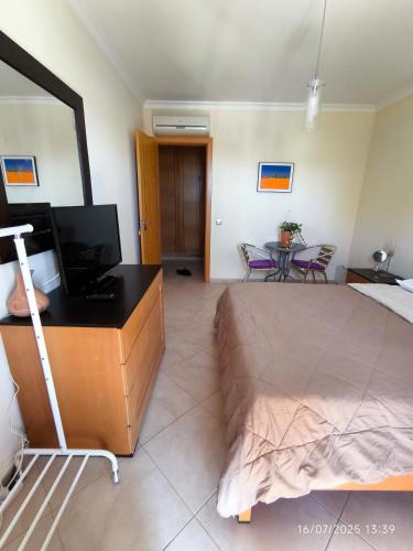 a bedroom with a bed and a desk with a television at Quarto Apartamento em Tavira in Bicas