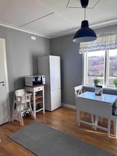 a living room with a table and a refrigerator at Naturnära Ängen Ödegården in Trollhättan