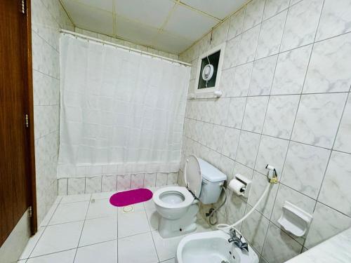 a white bathroom with a toilet and a sink at Basma Residence Hotel Apartments in Sharjah
