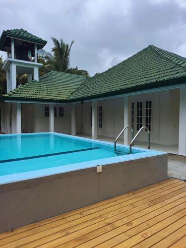a swimming pool in front of a house at The Shenu Lake House in Dandugama