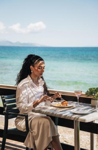 a woman sitting at a table with a plate of food at Golden Coast Suites in Kipseli