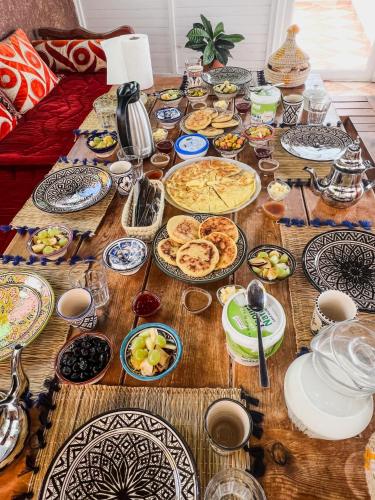 a wooden table with plates of food on it at Dar Surfana Morocco in Aourir