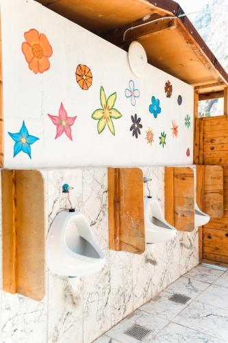 a bathroom with three urinals and flowers on the wall at Butterfly Valley Seaside Glamping in Oludeniz