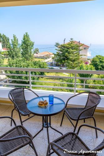 a table and chairs on a balcony with a view of the ocean at Drosia Apartments in Kypseli