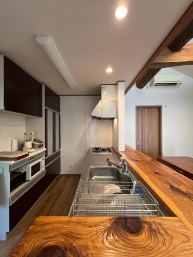 a kitchen with a sink and a wooden counter top at moksa House ヒリゾ浜まで車で10分ゆったりNetflixコンビニとスーパーは7分 in Kanō