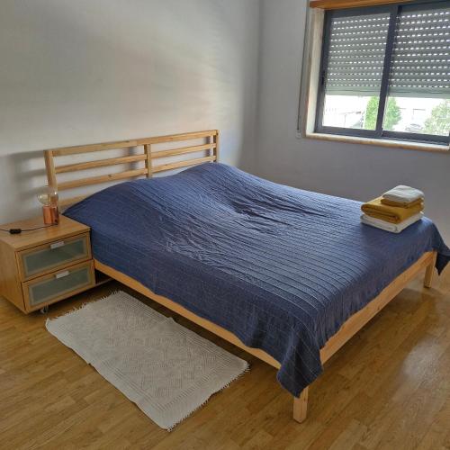a bedroom with a bed with a blue comforter and a table at Apartamento do Paço do Lumiar in Lisbon