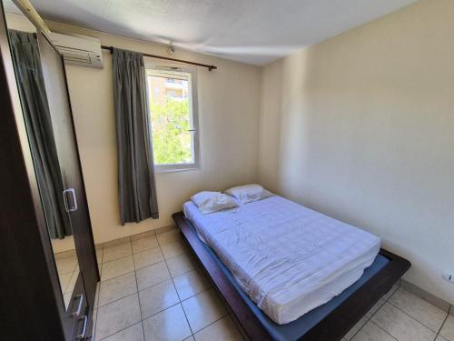 une petite chambre avec un lit et une fenêtre dans l'établissement T2 duplex dans résidence sécurisée, parking privé, piscine, climatisation, internet, à La Seyne-sur-Mer