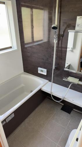 a bathroom with a shower and a bath tub at コンドミニアム海のまんまえ荘 in Ōda