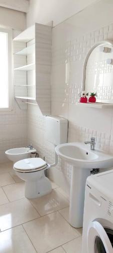 a white bathroom with a toilet and a sink at TORRE LAPILLO Fronte Mare in Centro con parcheggio coperto in Torre Lapillo