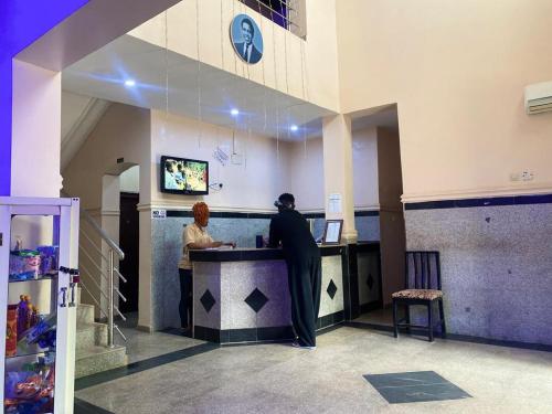 two people standing at a counter in a restaurant at Havilah Blu Hotel and Suites in Nnewi
