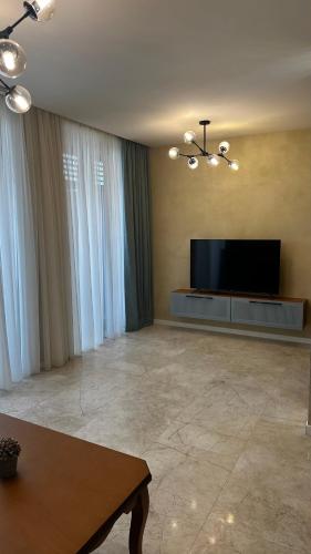 a living room with a flat screen tv and a table at Sea Breeze Resort, Beachfront apartment with a balcony and sea view in Nardaran