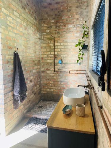 a bathroom with a sink and a brick wall at Apple Cottage in Grabouw