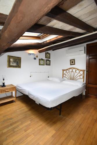 a large white bed in a room with wooden floors at Appartamento VIAROMA58 - Vicinissimo al mare con clima e posto auto in Marina di Campo