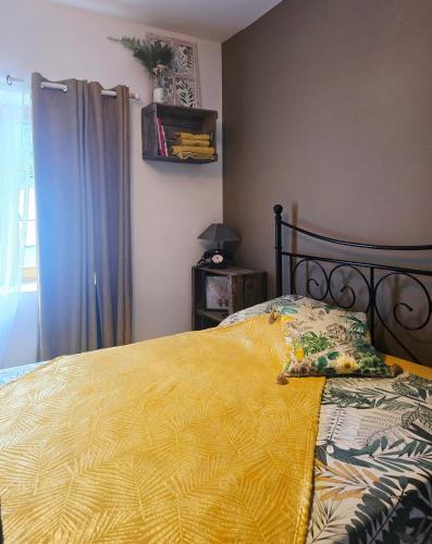 a bedroom with a bed with a yellow blanket at La Maison des Oiseaux in Crouzilles