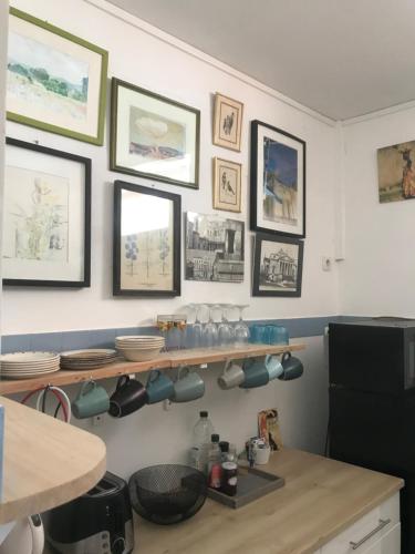 une cuisine avec une étagère avec de la vaisselle et des tableaux au mur dans l'établissement BEACH House CLODINET, à Saint-Palais-sur-Mer