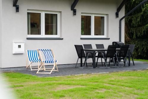 a table and chairs in front of a house at Lavender domek na Kaszubach - Przechlewo in Przechlewo