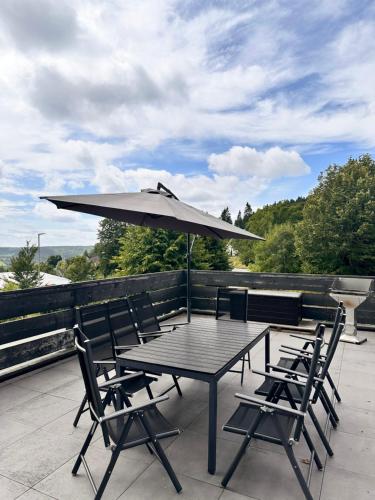 a table and chairs with an umbrella on a patio at Chalet Schneeglück Winterberg mit Sauna Terrasse Grill 11 Gäste in Winterberg