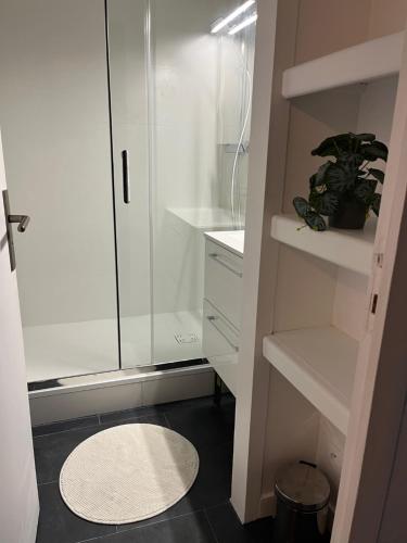 une salle de bain blanche avec une douche en verre et un tapis dans l'établissement APPART 4 PERS. BALCON & PARKING - PLAGE & COMMERCES, à Arcachon