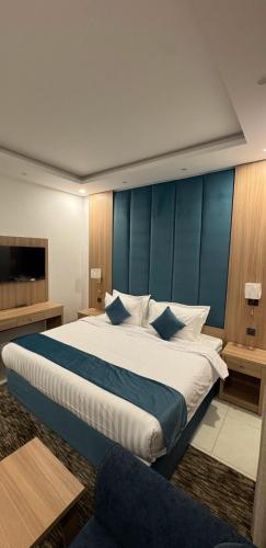 a bedroom with a large bed with a blue wall at جود المدينة للإجنحة الفاخرة in Medina
