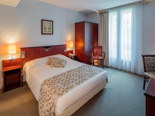 um quarto de hotel com uma cama e uma cadeira em Noemys Neris Montlucon - hotel restaurant em Néris-les-Bains