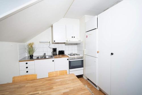 a kitchen with white appliances and a wooden table at Ljus & Fräsch lägenhet nära isaberg in Anderstorp