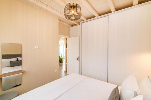 ein Schlafzimmer mit einem weißen Bett und einem Kronleuchter in der Unterkunft Horizon Hill Villa in Tinos