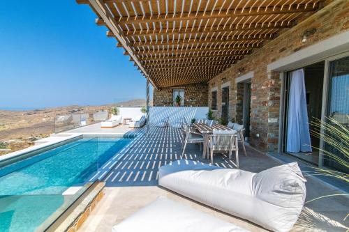 Villa mit einem Pool, einem Tisch und Stühlen in der Unterkunft Horizon Hill Villa in Tinos