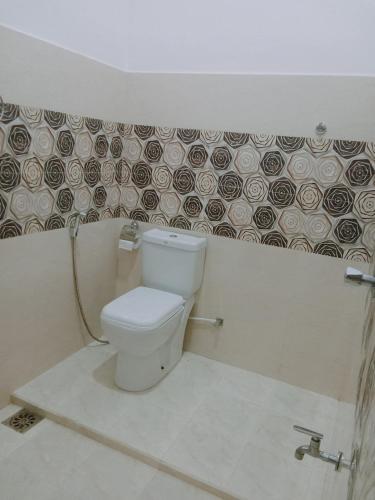 a bathroom with a toilet and a tile wall at Ops Poinix Hotel in Weerawila