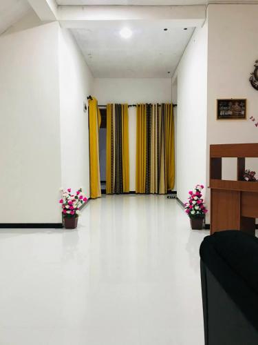a room with white floors and yellow curtains and flowers at Ops Poinix Hotel in Weerawila