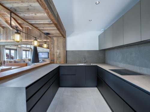 une cuisine avec des armoires noires et un comptoir dans l'établissement Duplex d'exception à Méribel: jacuzzi, sauna, skis aux pieds - FR-1-565-76, à Les Allues