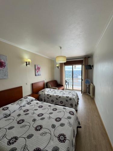 una camera d'albergo con due letti e un balcone di Flor Do Douro - Comércio e Hotelaria, Lda a Miranda do Douro