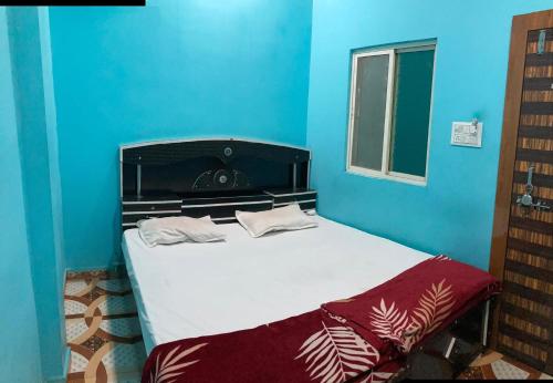 a bed in a room with a blue wall at Ramashrya Homestay Peaceful Stay Near Mahakal & Railway Station in Ujjain