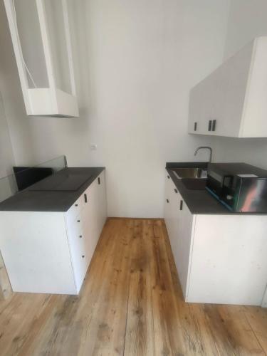 a kitchen with white cabinets and a wooden floor at Prealba 2 in Levanto