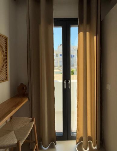 a window with curtains in a room with a view at Due Venti Downtown Suites Naxos Junior in Naxos Chora