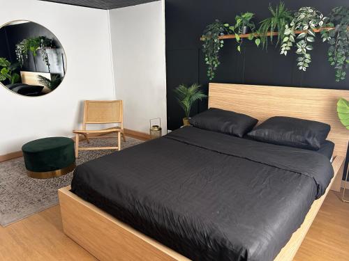 une chambre avec un lit avec des draps noirs et des plantes dans l'établissement Guibert Home - Studio 2 personnes, à Villeneuve-le-Roi