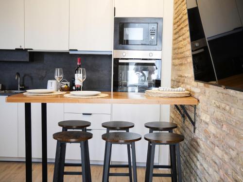 a kitchen with a counter with stools and a microwave at Precioso ático con vistas en el centro de Pamplona in Pamplona