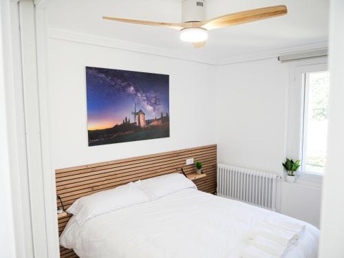 a bedroom with a white bed and a ceiling fan at Precioso ático con vistas en el centro de Pamplona in Pamplona