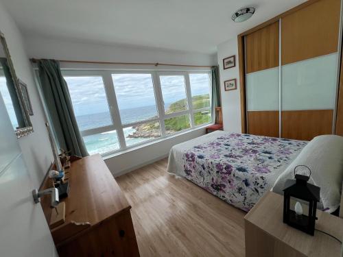 a bedroom with a bed and a large window at Ensenada Dichosa in Suances