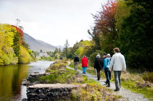 a group of people walking down a path next to a river at Ballynahinch Castle Hotel in Ballynahinch